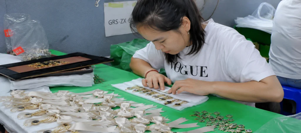 factory worker inspecting ribbon bows metal charms qc